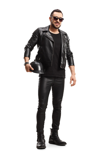 Full length portrait of a biker in leather jacket and pants holding a leather helmet isolated on white background