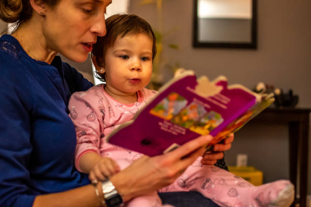 Toddler celebrating Christmas. Young girl and her godmother reading a book received for Christmas. pics of the godmother stock pictures, royalty-free photos & images