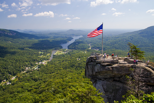 Chimney Rock, North Carolina, USA - September 21, 2014: Group of tourists take in the view of Lake Lure and the surrounding from the top of Chimney Rock in the Appalachian Mountains of North Carolina.