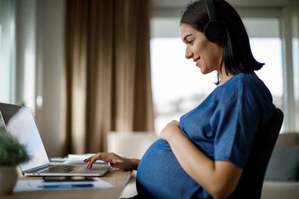 istock Pregnant woman with headphones using laptop 1277221041