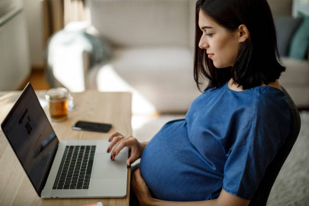 istock Pregnant woman using laptop at home 1277221098