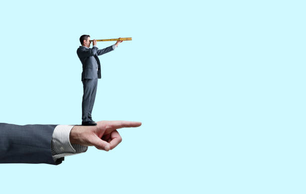 istock Man Standing On Pointing Hand looks Through A Spyglass 1277222915