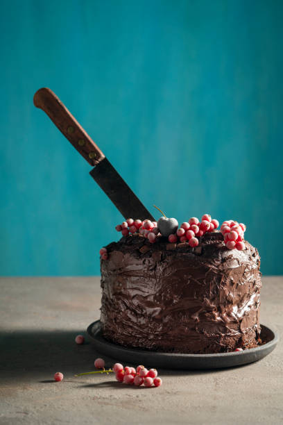 Chocolate cake with red currant frozen berries on top and cutting knife