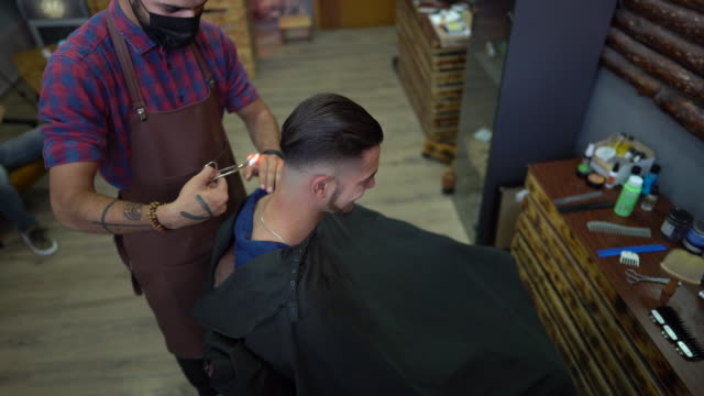 Barber trimming man's hair burning it by fire at barber shop