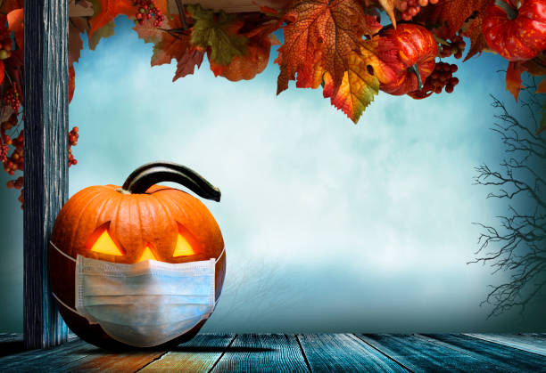 istock Jack O'Lantern Wearing Protective Face Mask On Porch Adorned With Autumn Leaves 1277230026