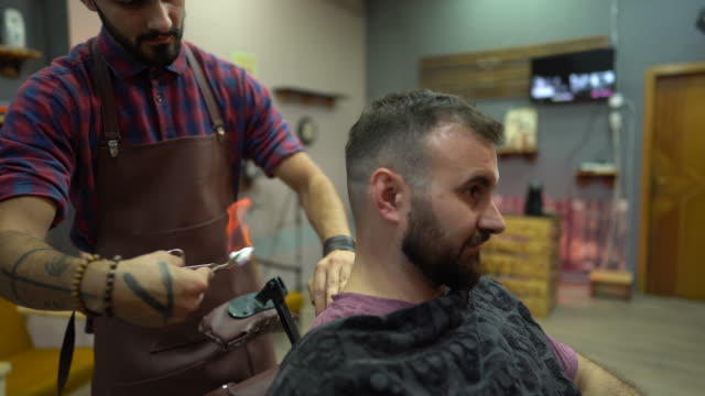 Barber trimming man's hair burning it by fire at barber shop