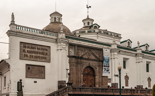 Quito, Ecuador - December 2, 2008: Historic downtown. Entrance to Museum of Metropolitan Cathedral on Independence Square is dark brown stone set in white facade.
