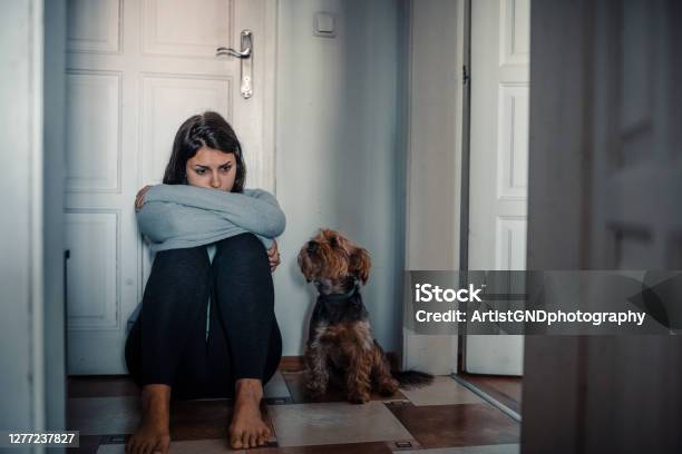 Woman With A Mental Problems Is Sitting Exhausted On The Floor With Her Dog Next To Her Stock Photo - Download Image Now