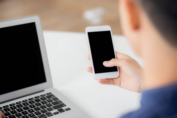 istock Hand of young man working with laptop computer and smartphone mockup on desk at home, notebook and phone display blank screen, freelance look message to internet, business and communication concept. 1277239876
