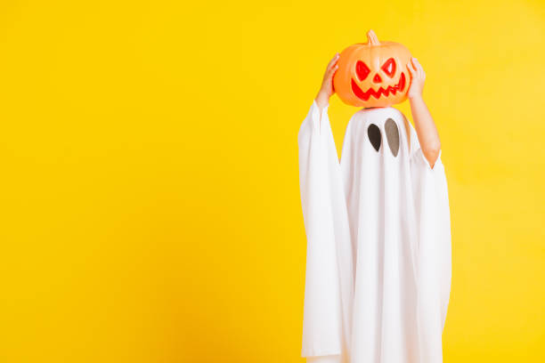 istock little cute child with white dressed costume halloween ghost scary he holding orange pumpkin ghost on hand 1277242520