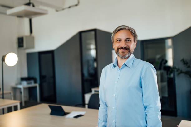 istock Smiling mature businessman standing in office looking at camera. 1277242816