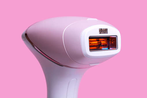 Photoepilator on a pink background. Hair removal tool