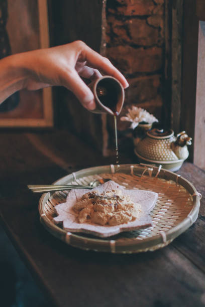 pouring brown sugar syrup en warabi-mochi o kinako mochi, albóndigas de bracken-starch sobre fondo vintage. postre tradicional japonés. - bracken starch fotografías e imágenes de stock