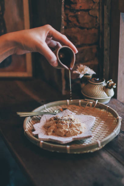 рука заливки коричневый сахарный сироп в вараби-моти или кинако моти, bracken-крахмал пельмени на винтажном фоне. японский традиционный десерт - bracken starch стоковые фото и изображения