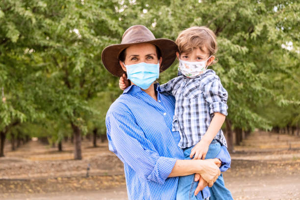 Caucasian Mature farmer woman posing with her son both wearing protective face masks