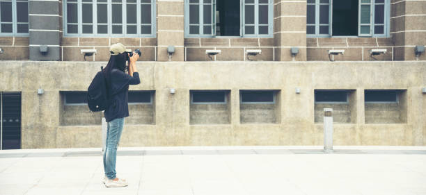 banner asian tourist using dslr professional camera travel on vacation. female young traveler with backpack and photo camera in old town with copy space. panoramic beautiful woman traveller backpack - reportage photographer photographing street imagens e fotografias de stock