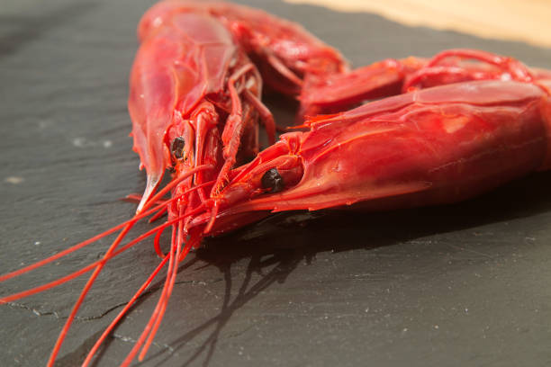 large raw red king prawns on a black background close up laid out in the form of a heart