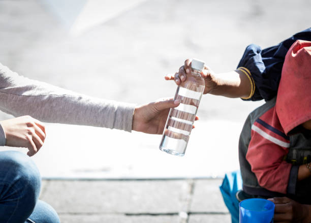 Detail of hand of homeless woman asking for money in the street Detail of woman's hand giving a bottle of water to a homeless person water crisis stock pictures, royalty-free photos & images