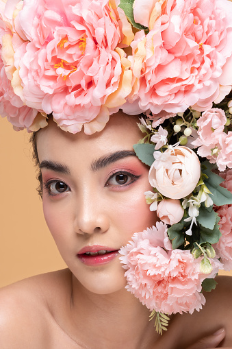Beauty Asian young woman with big bouquet flowers on head smile with clean fresh skin Happiness and cheerful with positive emotional on Beige background,Beauty Cosmetics and Facial treatment Concept