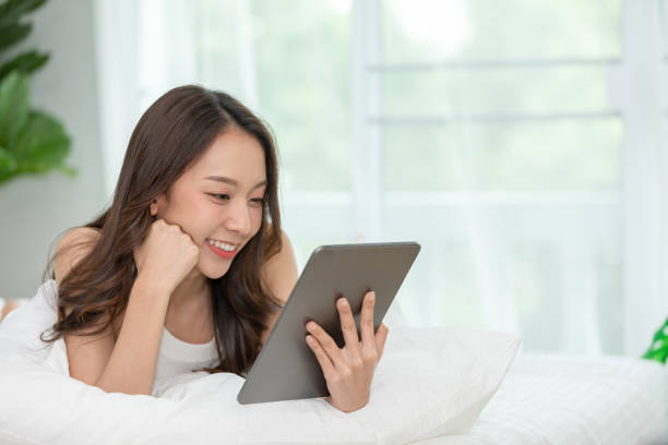 istock Beauty Asian woman smile and using computer tablet on her bed at home,using social media and multimedia on tablet relax in holiday 1277250033