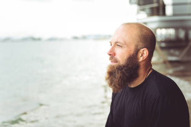 istock Man with beard at the beach looking off into the distance 1277252910