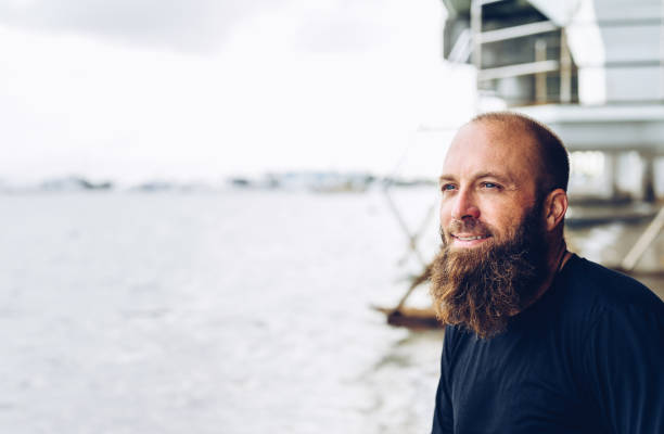 istock Man with beard at the beach looking off into the distance 1277252960