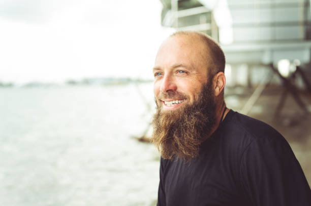 istock Man with beard at the beach looking off into the distance 1277252967