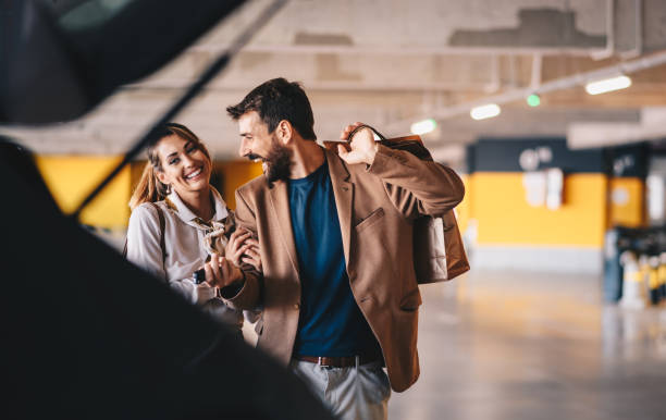 Young attractive fashionable couple walking towards their car and attending to put shopping bags into a trunk. stock photo