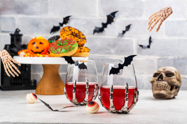 Halloween trick or treat party table Halloween kids party table with candy corns, ginger cookies, spooky donuts and cranberry drinks. Happy halloween background. Copy space skull photos stock pictures, royalty-free photos & images