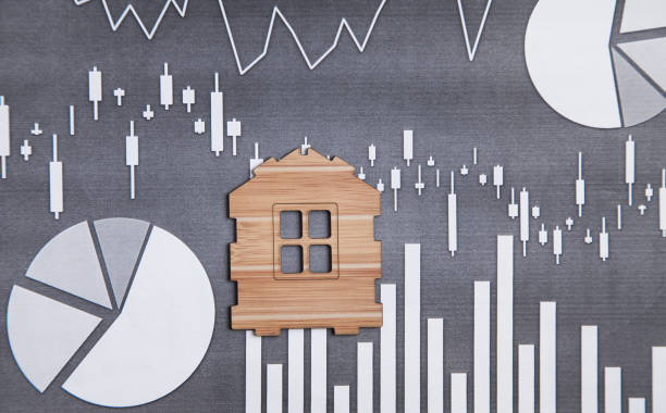 istock Wooden house model on financial graphs. 1277274531