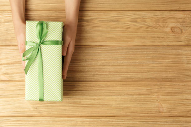 istock gift box in the hands on a wooden background 1277274750