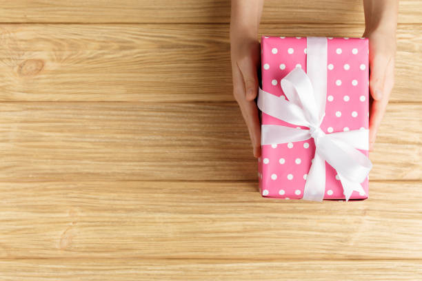 istock gift box in the hands on a wooden background 1277276046