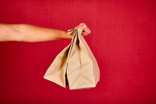 istock Closeup courier hand holding grocery paper bag, delivery service 1277278028