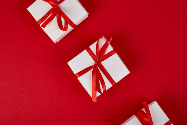 istock Luxury white gift boxes with red ribbon on red background. 1277278061