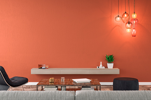 Empty nostalgic living room with gray sofa, lounge chair, pouffe, table and decoration in front of brick orange plaster wall. Low wooden shelf in the middle, suitable for TV. 3D rendered image.