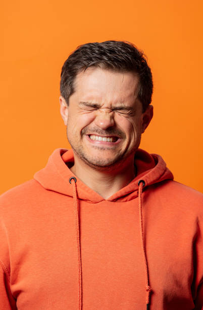 guy in orange hoodie squints in displeasure
