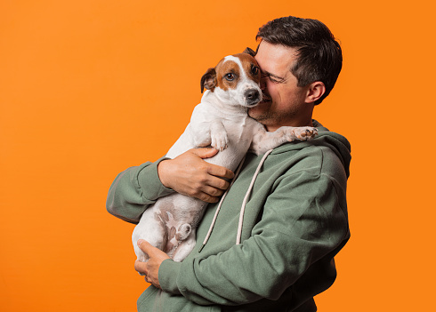 Happy smiling guy with a dog on orange background