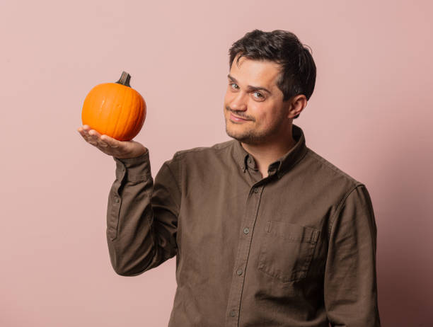 istock white guy with pumpkin on pink background 1277279931