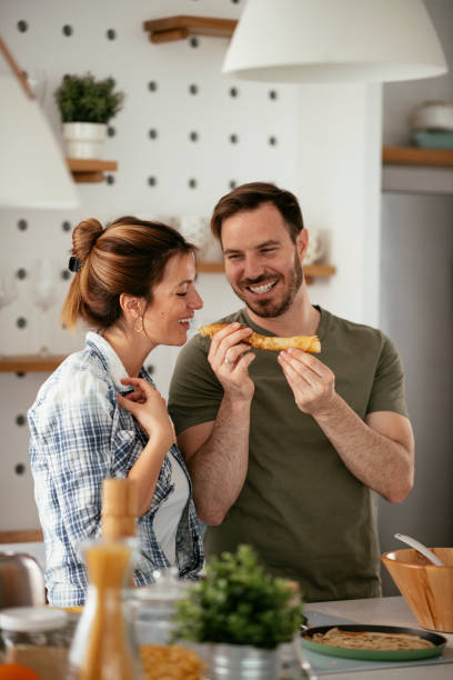 Young couple making pancakes at home