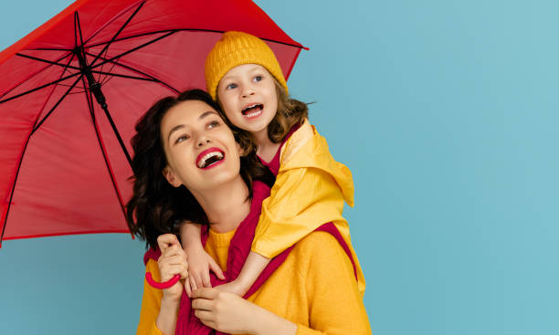 Family with red umbrella Happy emotional child and mother laughing and hugging. Family with red umbrella on colored teal background. umbrella photos stock pictures, royalty-free photos & images