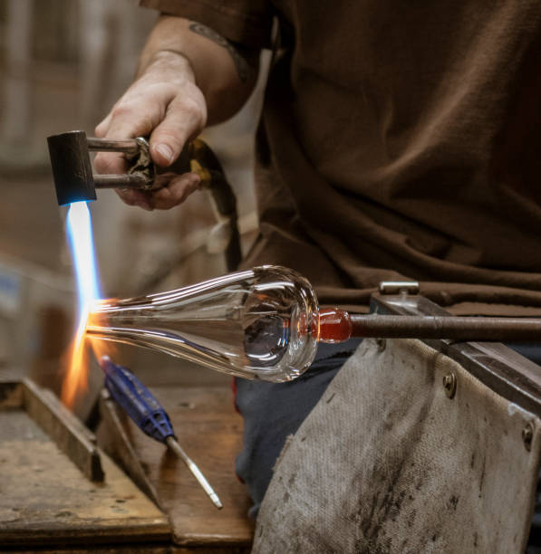 A glass blowing artist forms a blob of glass into a vessel using a gas torch A glass blowing artist forms a blob of glass into a vessel using a gas torch in Vermont hand blown glass stock pictures, royalty-free photos & images