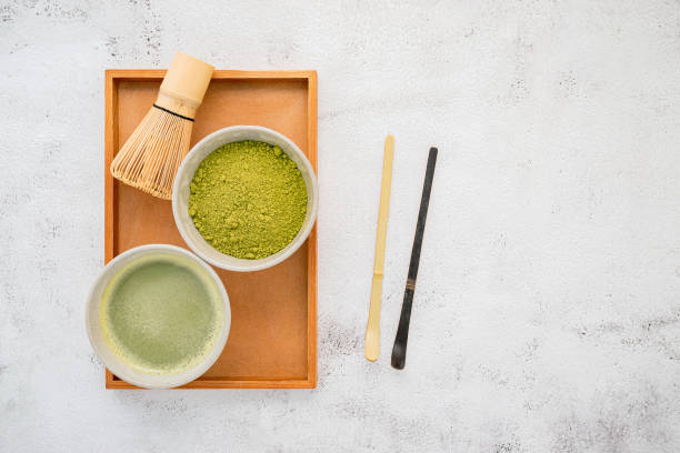 istock Matcha green tea powder with bamboo matcha whisk brush  setup on white concrete background . 1277287747