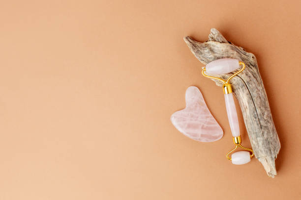 istock Jade face rollers and stone for beauty facial massage therapy. Flat lay on beige background with woody plant root - modern, trendy creative still life card, stylish luxury wellness concept 1277288331