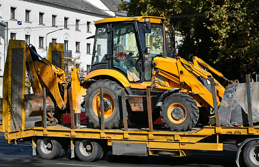 A closeup of a yellow construction vehicle, backhoe loader model on a white background