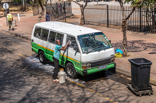 African taxi operator washing his vehicle, smiling and happy, in Johannesburg city centre, Johannesburg is also known as Jozi, Jo'burg or eGoli and is the largest city in South Africa.