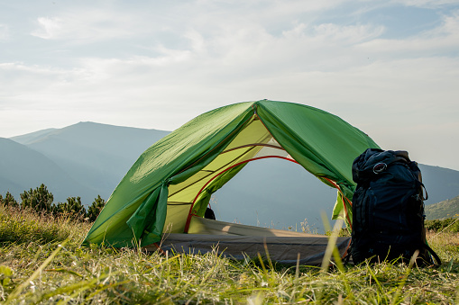 view of tourist tent in mountains at sunrise or sunset. Camping background. Adventure travel active lifestyle freedom concept. Summer vacation
