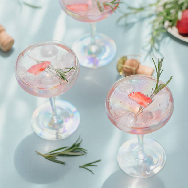 istock Summer drink with white sparkling wine. Homemade refreshing fruit cocktail or punch with champagne, strawberries, ice cubes and rosemary on light blue background. 1277296797