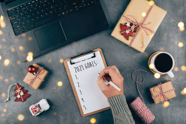 Happy New Year 2021. Woman's hand writing 2021 Goals in notebook. Top view, flat lay
