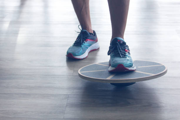 Mans legs in trainers testes balance board with one leg.