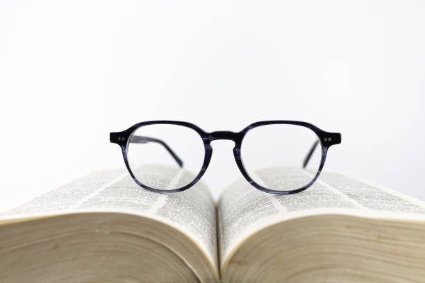istock Close-up of a reading glasses on an open book on a white background 1277302603